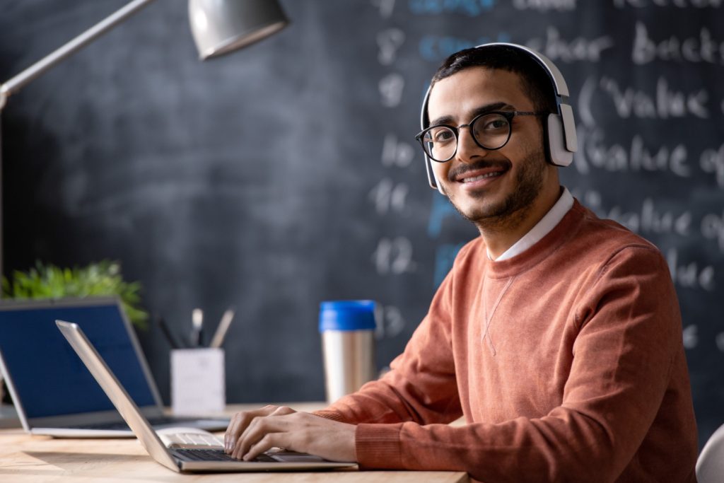 The Bright Future of 10 Different Continuous Professional Learning Opportunities 5 young smiling it manager with laptop looking you while listening music headphones during work office 1024x683 1